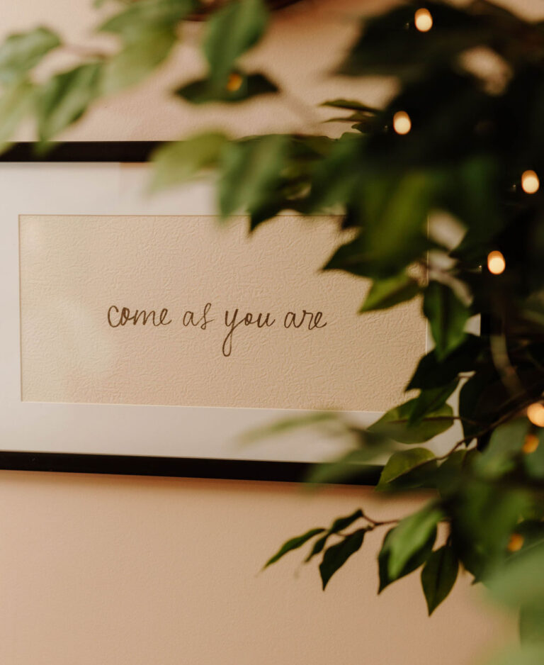 Framed Come As You Are print beside a plant in a Hope and Wholeness office