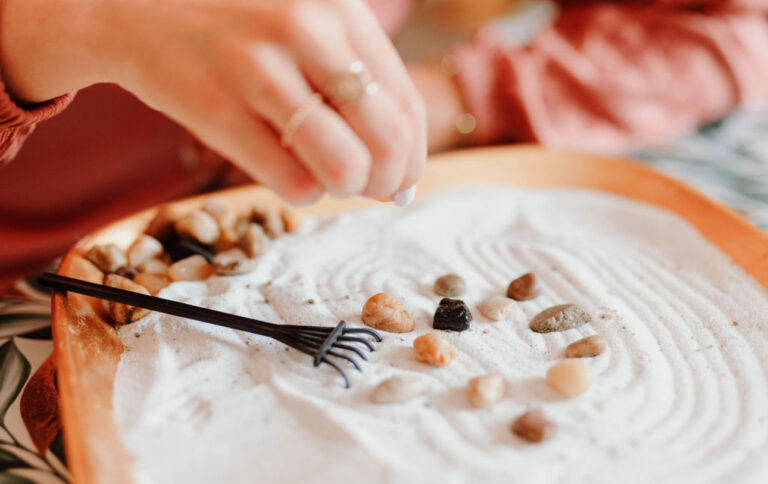 Hand raking a small sand garden in a Hope and Wholeness therapy room