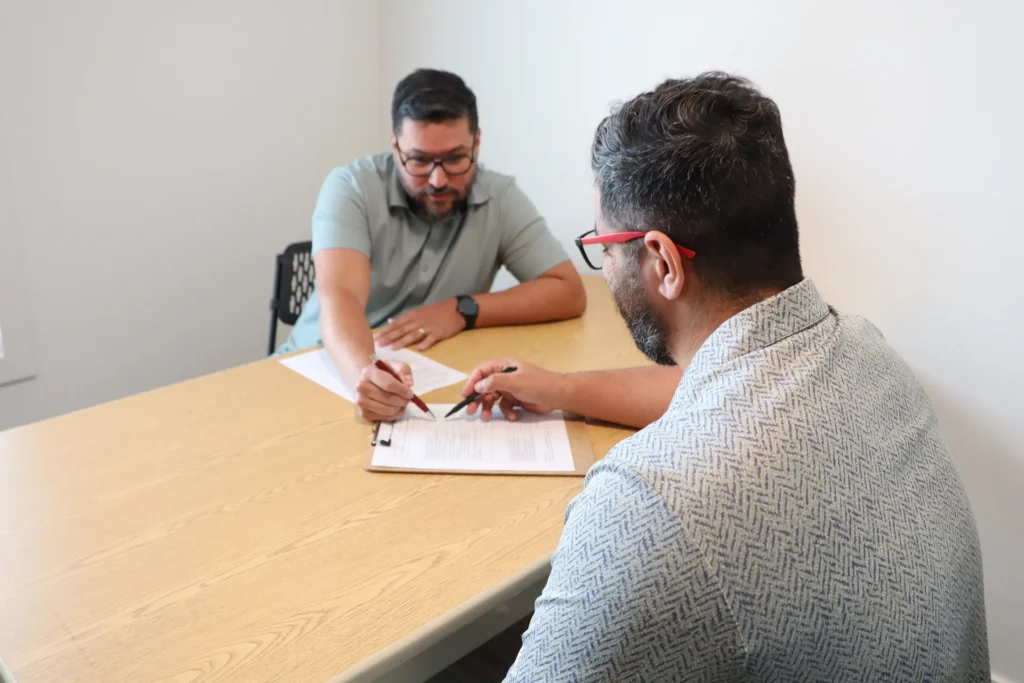 Clinician reviewing intake paperwork with an adult client at a table