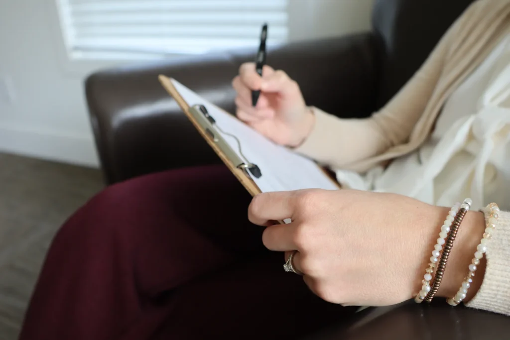 Close-up of a therapist writing notes on a clipboard